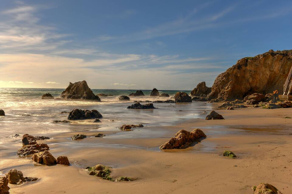 A rocky beach with large boulders and a cliff.