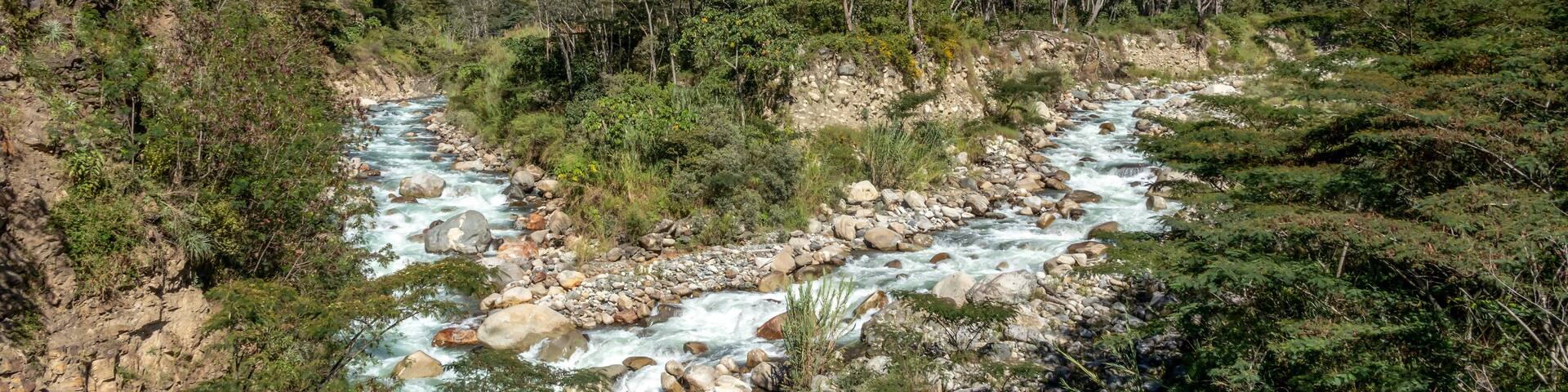 A river flowing through a mountainous valley with lush greenery and rocky terrain.