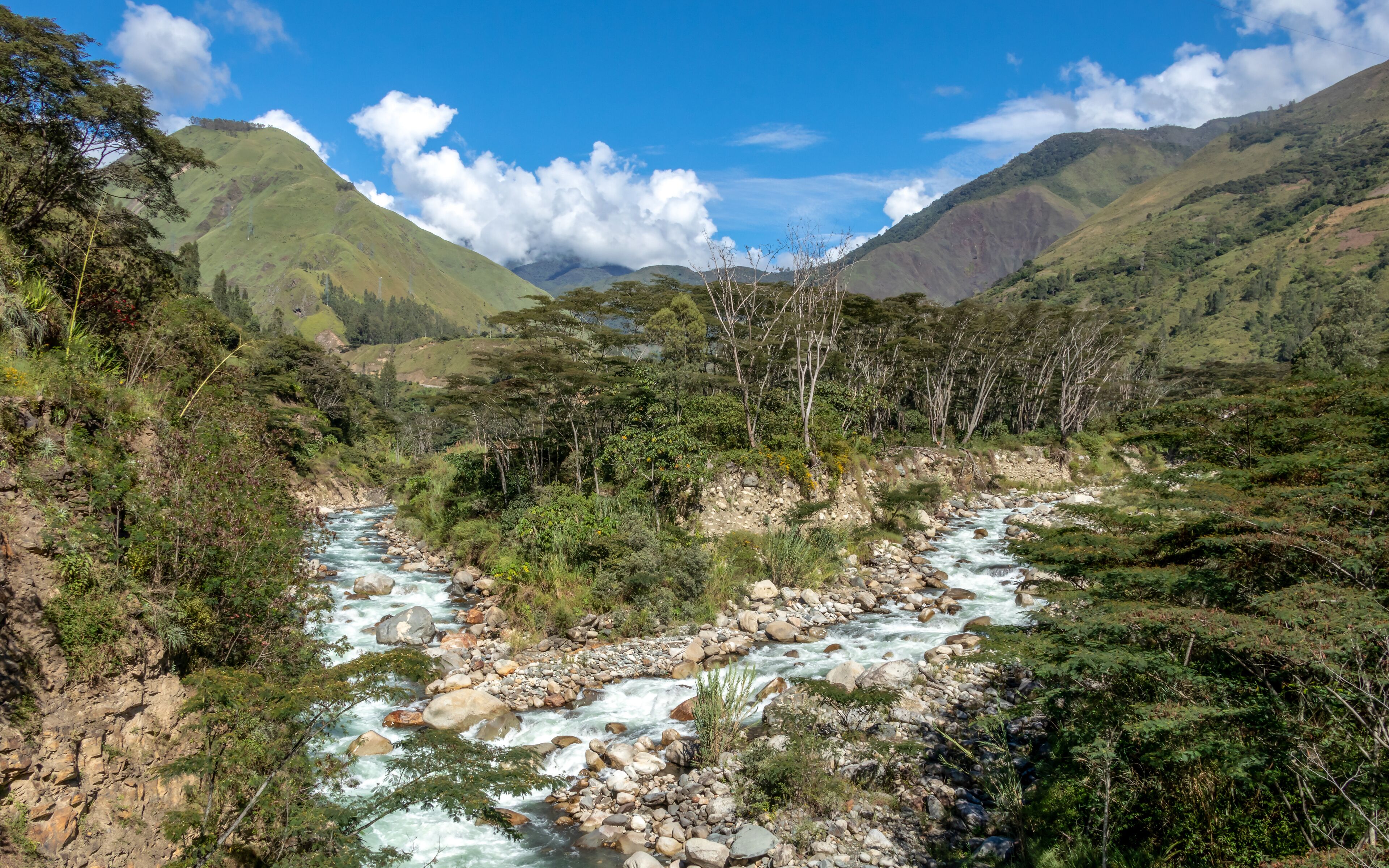A river flowing through a mountainous valley with lush greenery and rocky terrain.