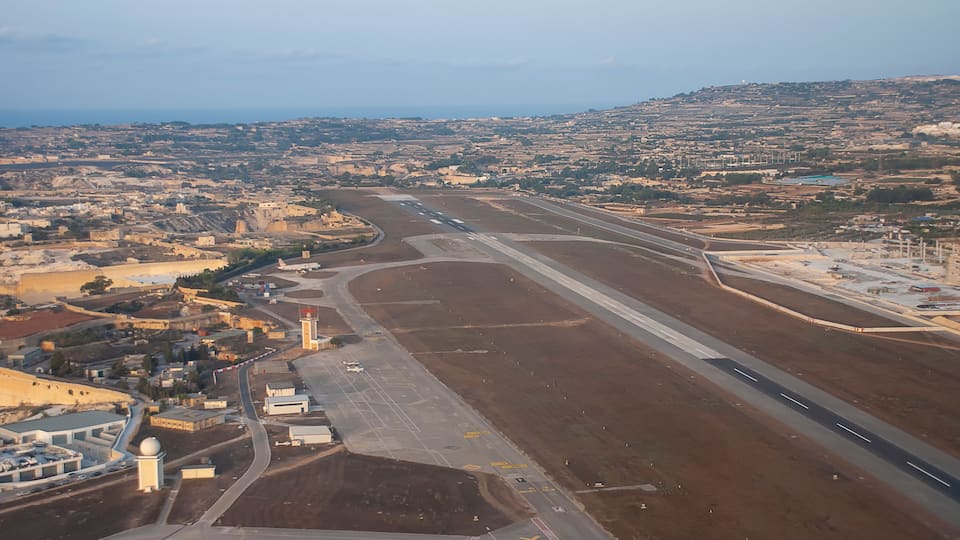 An aerial view of an airport with multiple runways and surrounding urban landscape.