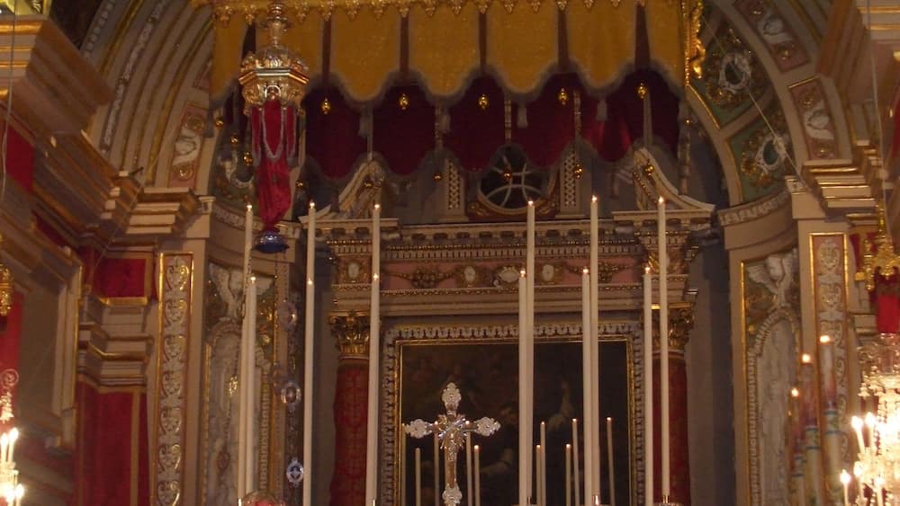 An ornate religious altar with golden decorations, statues, and candles.
