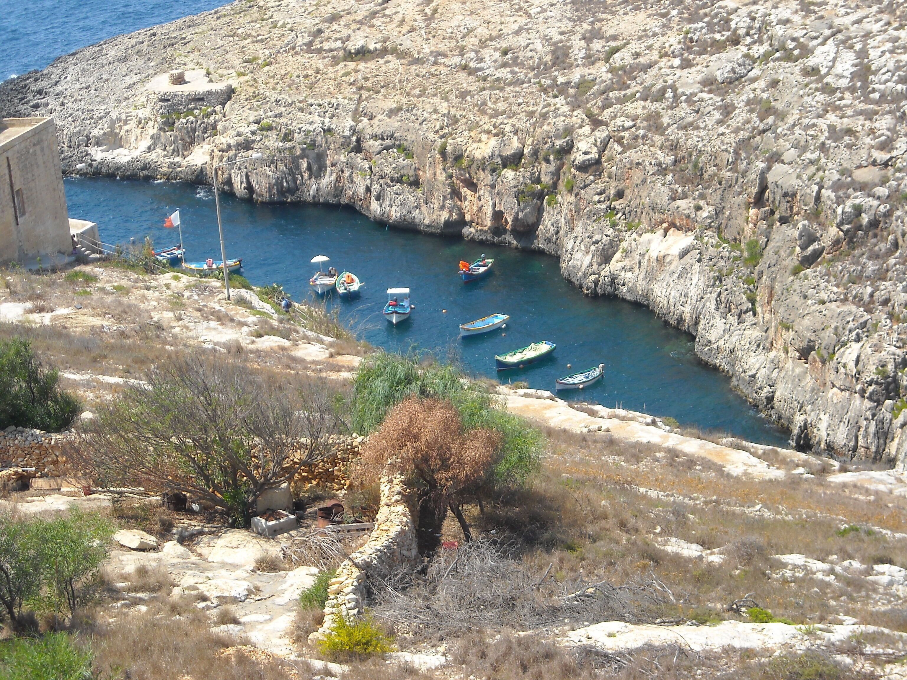 A rocky coastal area with several small boats anchored near the shore.