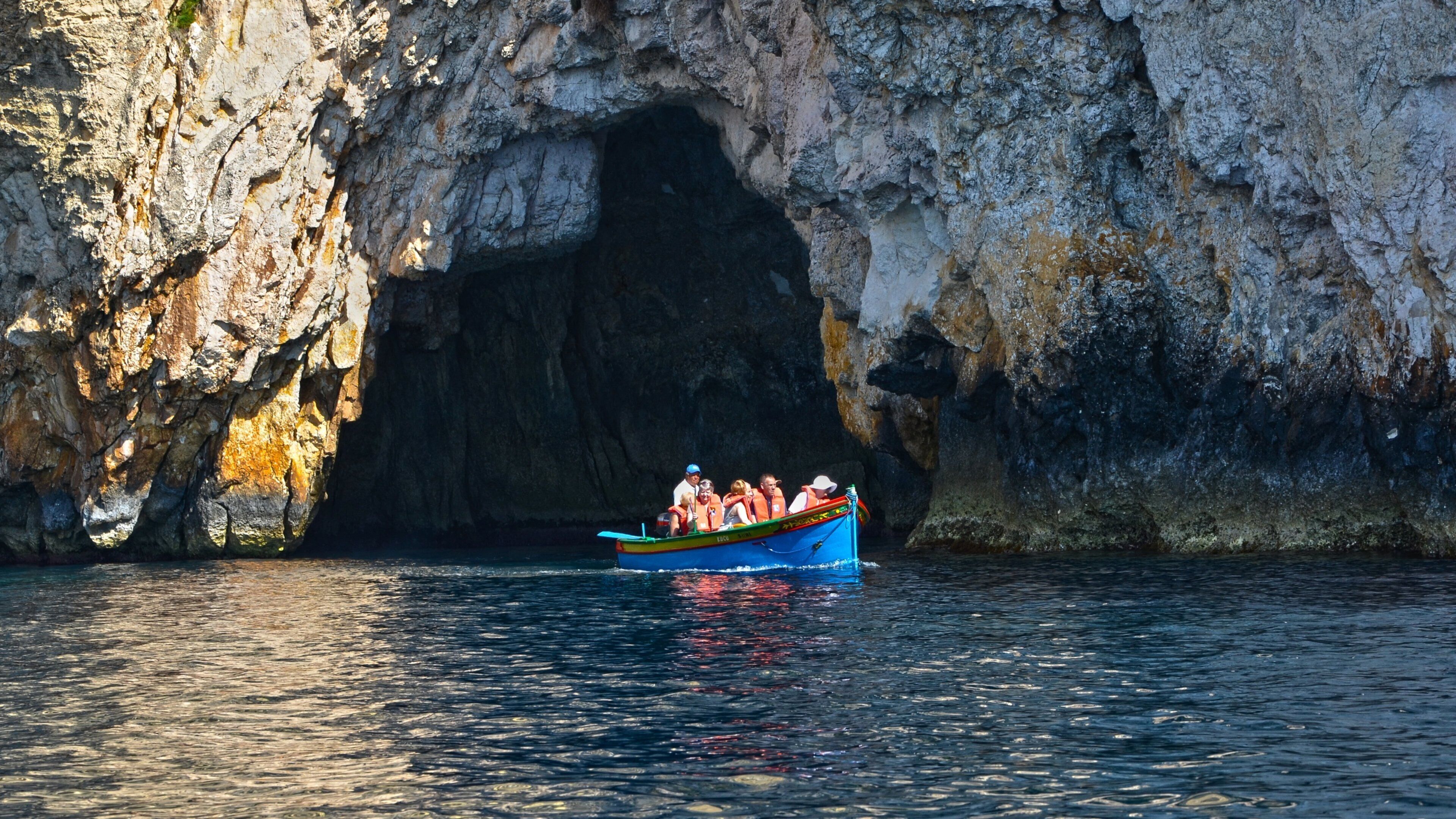 Zurrieq showing caves and boating as well as a small group of people