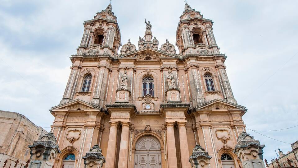 A historic church with ornate architecture, including a large central door and two bell towers.