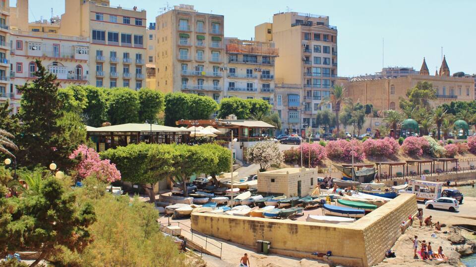 A coastal town with boats, a sandy beach, and historic buildings.