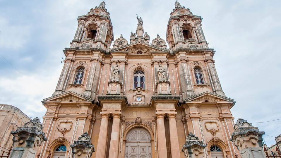A historic church with ornate architecture, including a large central door and two bell towers.