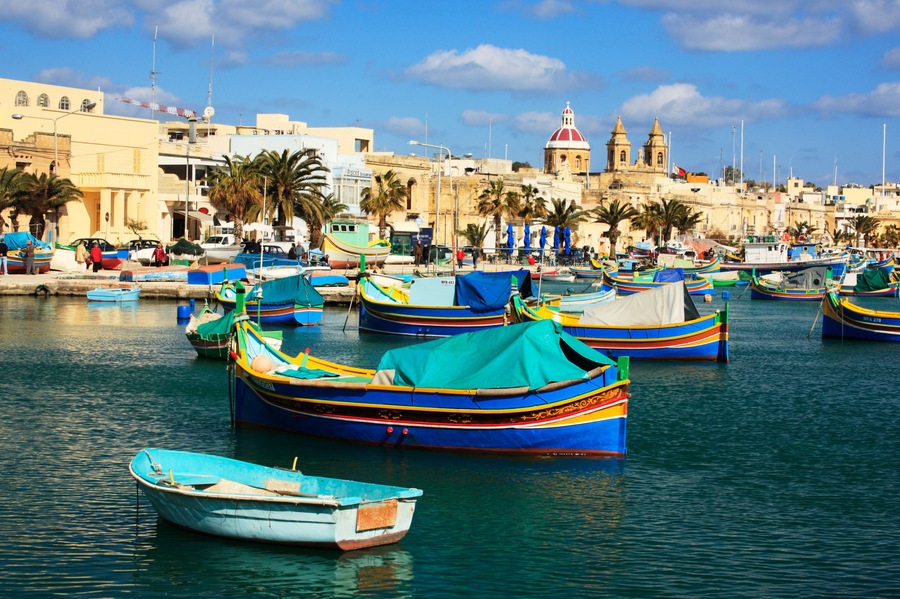 Brightly painted boats called Luzzu decorate the harbor at Marsaxlokk in Malta