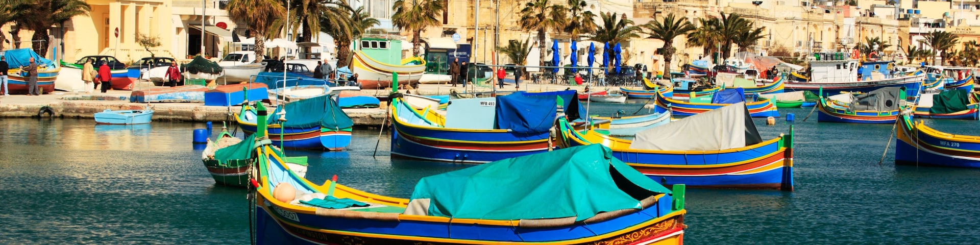 Brightly painted boats called Luzzu decorate the harbor at Marsaxlokk in Malta