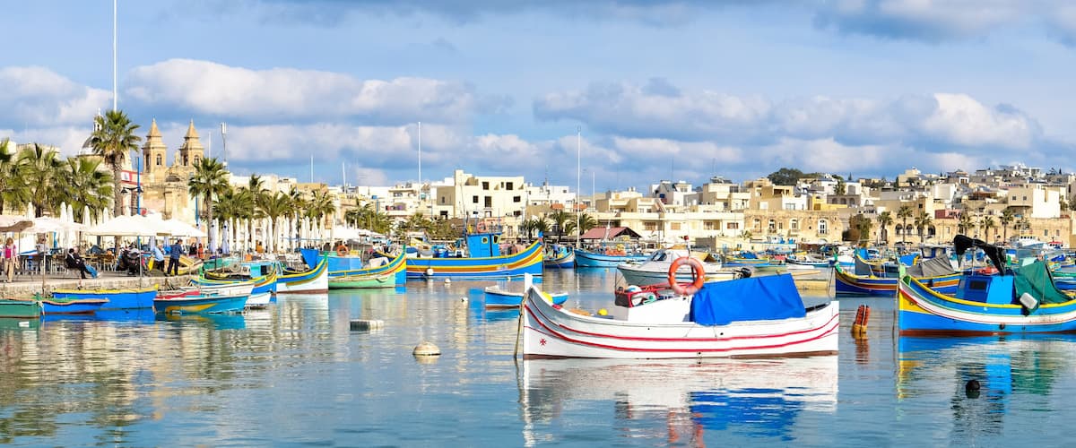 A harbor with colorful boats, a historic building, and a coastal town.