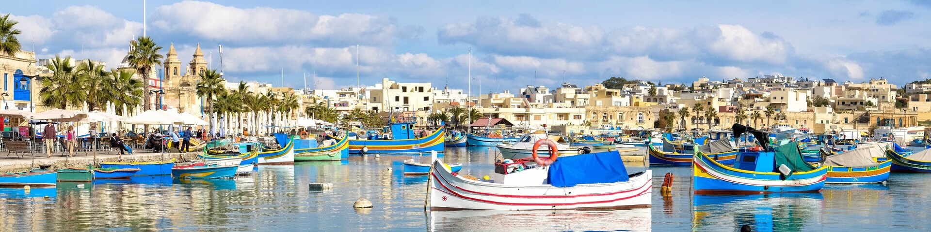 A harbor with colorful boats, a historic building, and a coastal town.