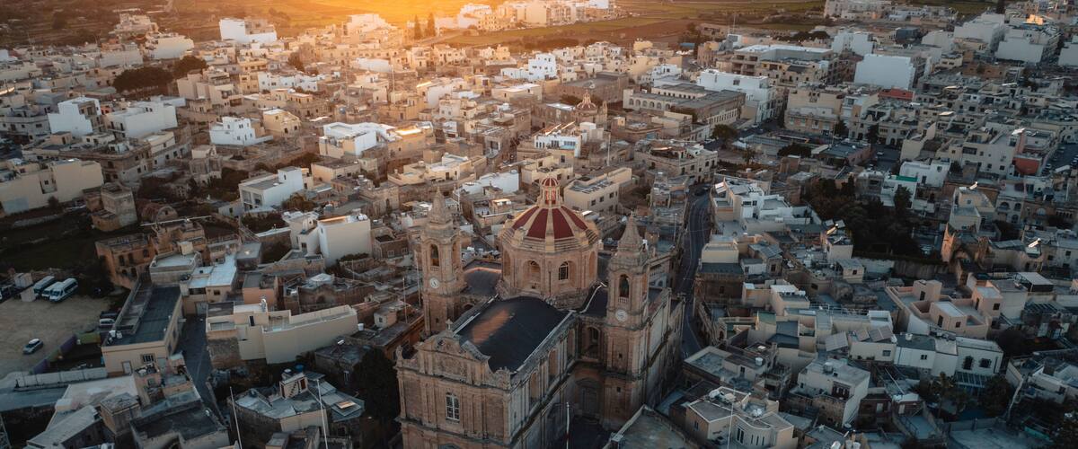 An aerial view of a densely packed urban area with a prominent historical building featuring a red dome and bell towers.