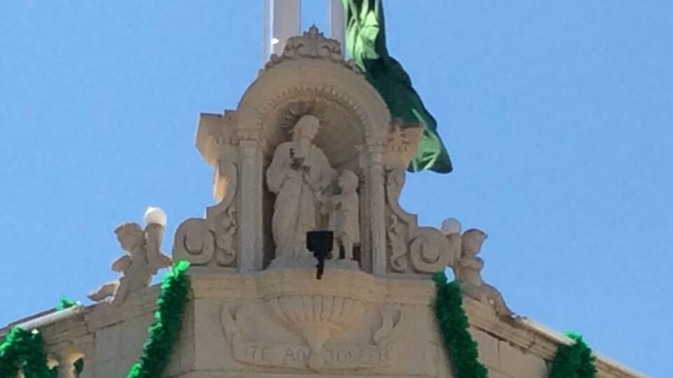 A monument with a statue, garlands, and a flag.