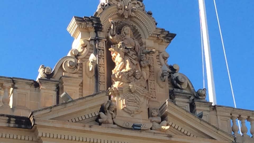 A detailed architectural sculpture with the inscription "MUZIKALI" on a building facade.