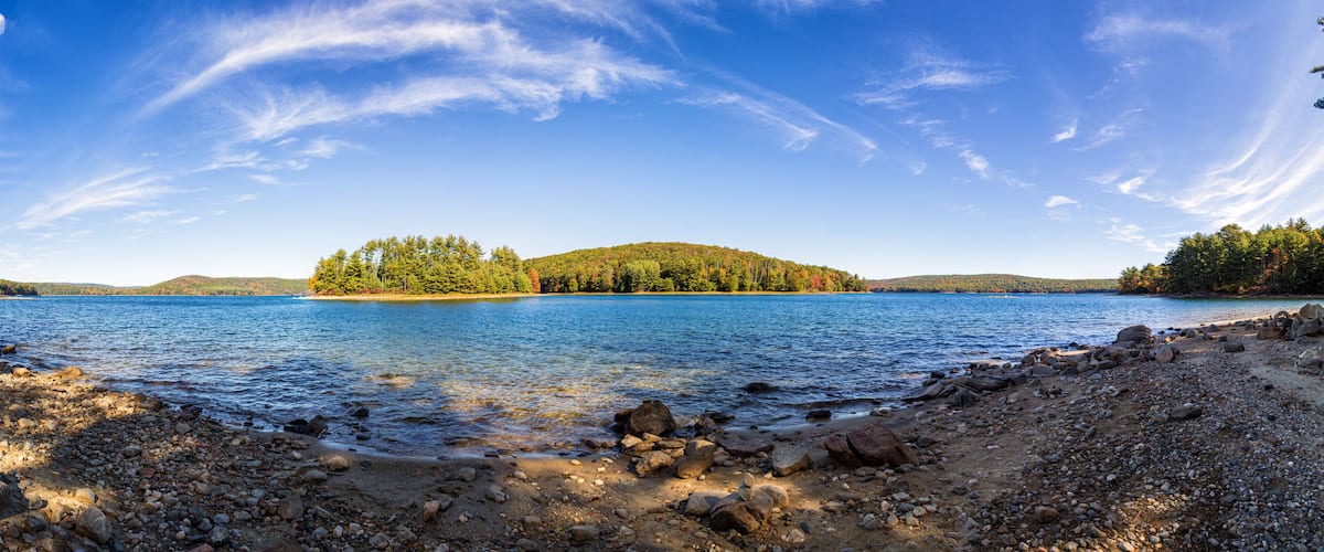 A lake with a rocky shoreline and a forested island.