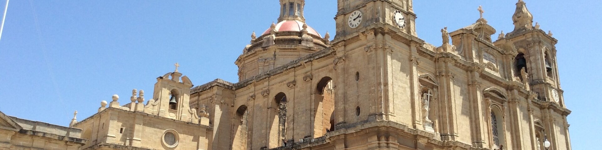 Una catedral histórica con una torre de campanas destacada y múltiples arcos.