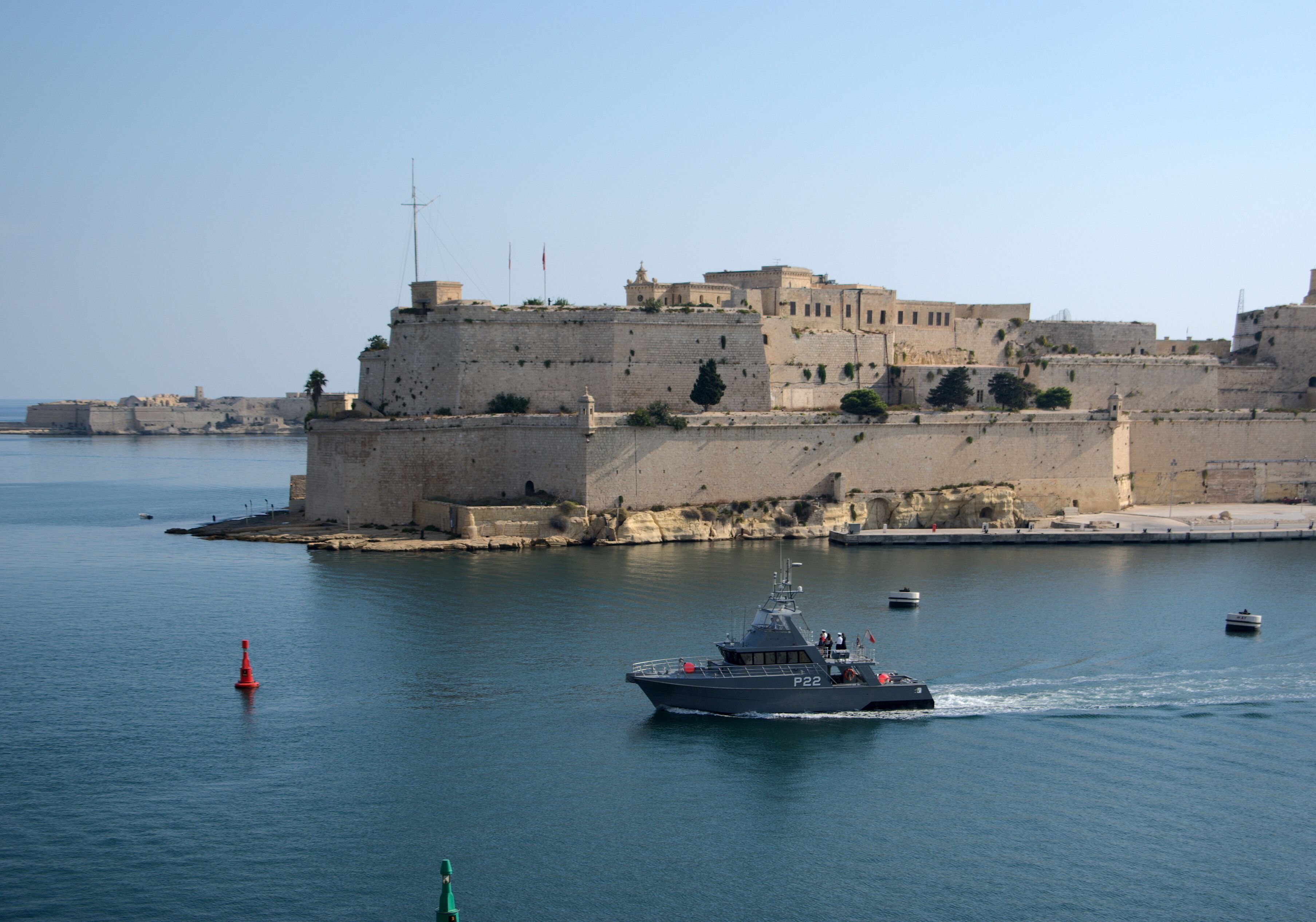 A coastal city with a fortified castle, calm waters, and a small boat.