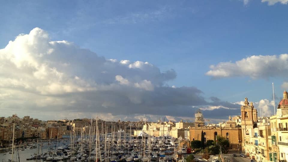 A harbor with numerous boats, a historic building, and a clear sky.