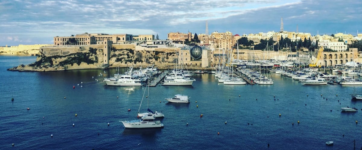 A harbor with numerous boats, a historic cityscape, and a clear sky.