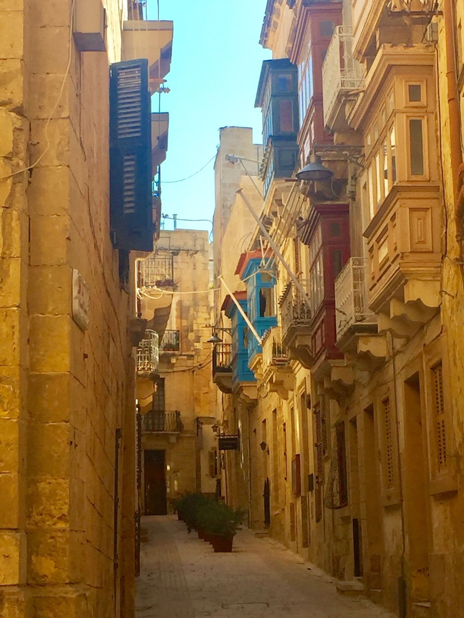 A narrow street flanked by multi-story buildings with balconies and traditional architecture.