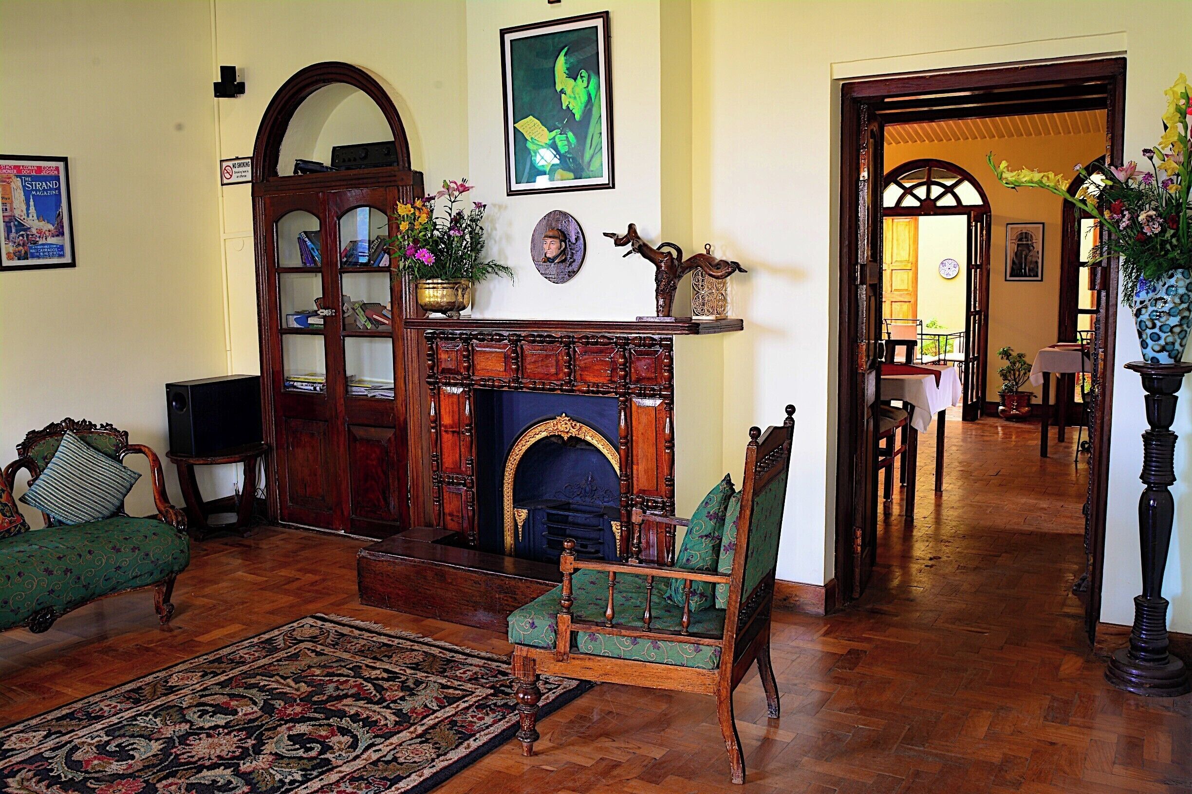 A traditional living room with a fireplace, green upholstered furniture, and a wooden cabinet.