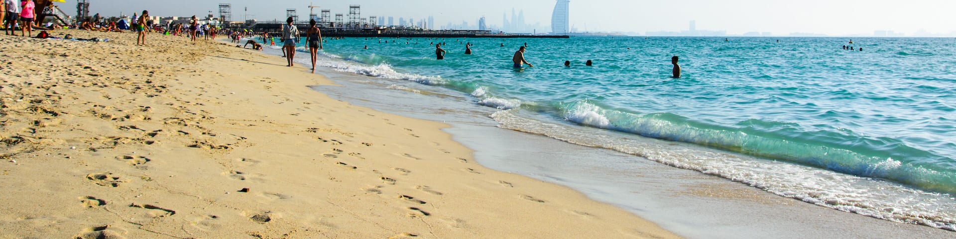 Dubai, United Arab Emirates, April 20, 2018: Kite beach in Dubai with many visitors and Burj Al Arab hotel in the background