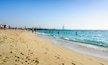 Dubai, United Arab Emirates, April 20, 2018: Kite beach in Dubai with many visitors and Burj Al Arab hotel in the background