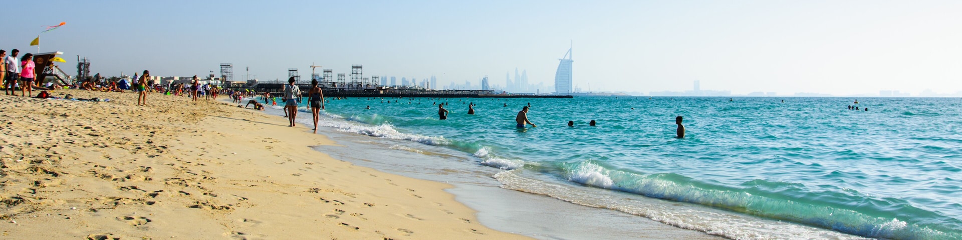Dubai, United Arab Emirates, April 20, 2018: Kite beach in Dubai with many visitors and Burj Al Arab hotel in the background