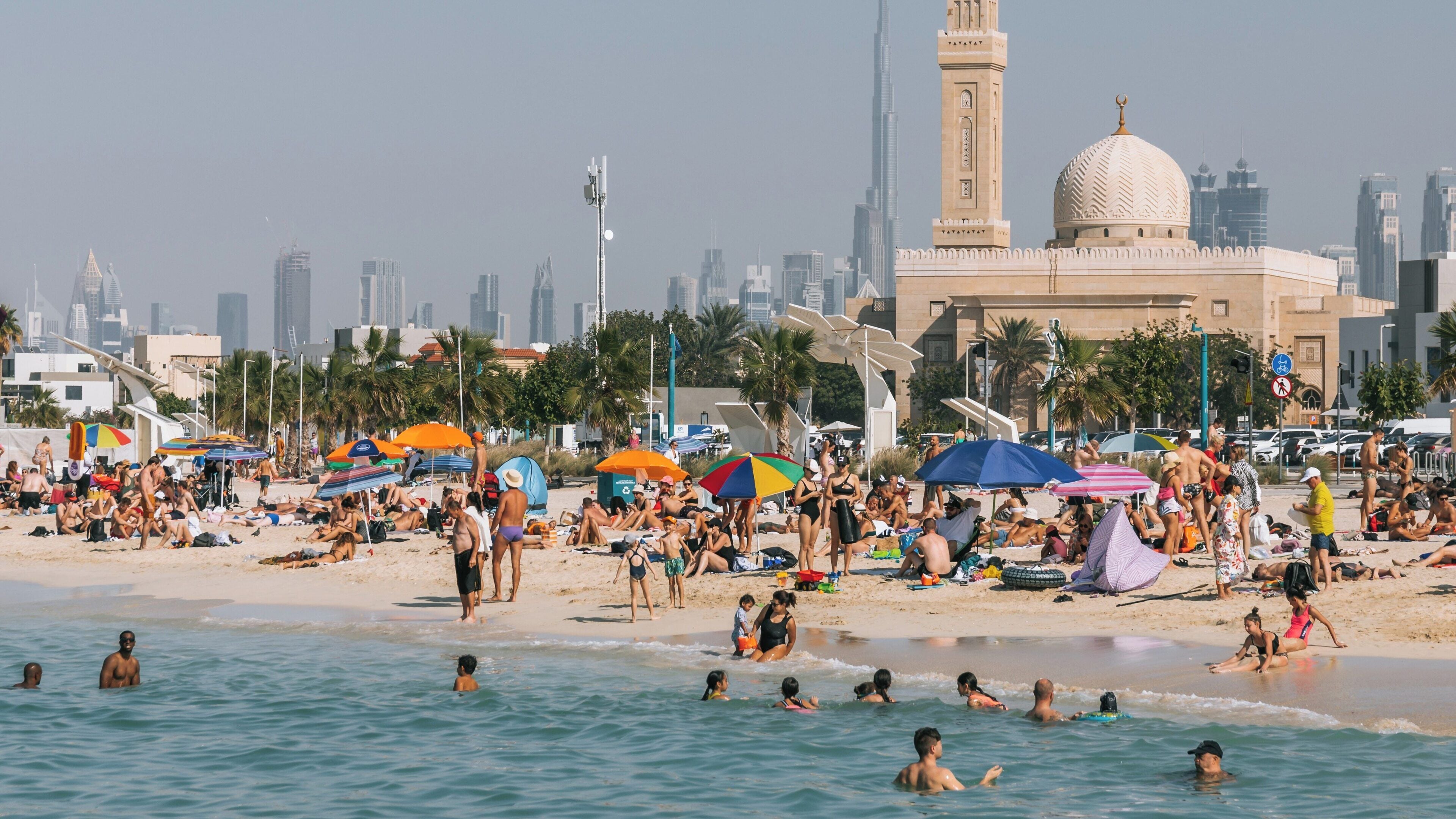 Vibrant summer day at Kite Beach in Umm Suqeim, Dubai with families enjoying the sun and sea near iconic landmarks