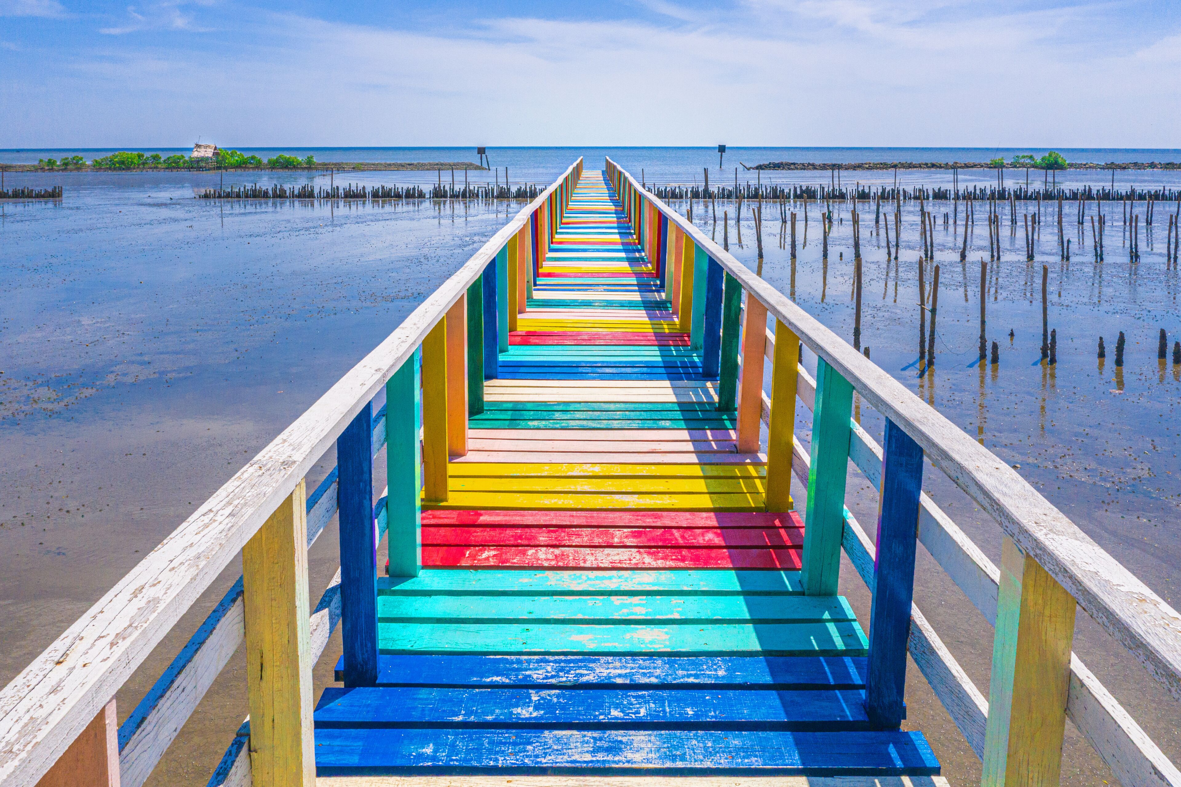 Rainbow bridge in Thailand.View of The colorful wood bridge extends into the sea under blue sky at samut sakhon province,Thailand.