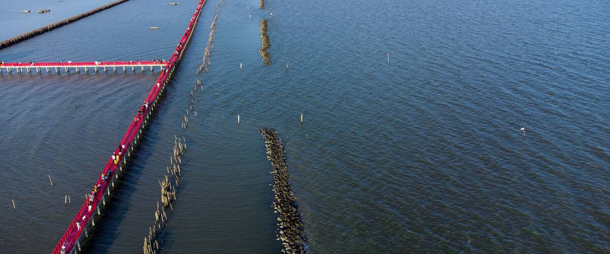 A long red bridge over a wide river with a clear sky.