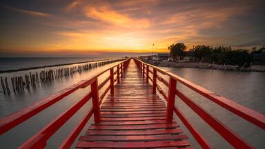 Red bridge in the evening with a beautiful sunset, Dolphin viewpoint, Samut Sakhon, Thailand.