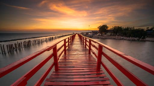 Red bridge in the evening with a beautiful sunset, Dolphin viewpoint, Samut Sakhon, Thailand.