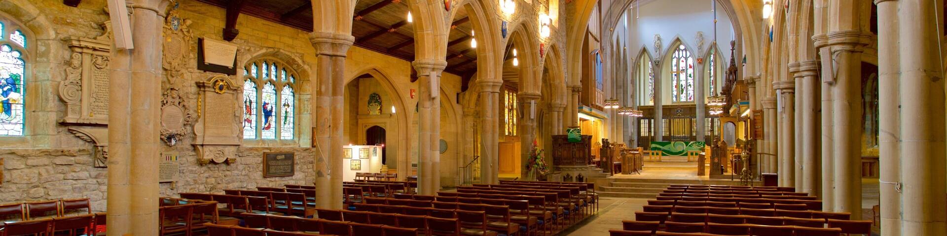 An interior of a church with wooden pews, stone arches, and stained glass windows.