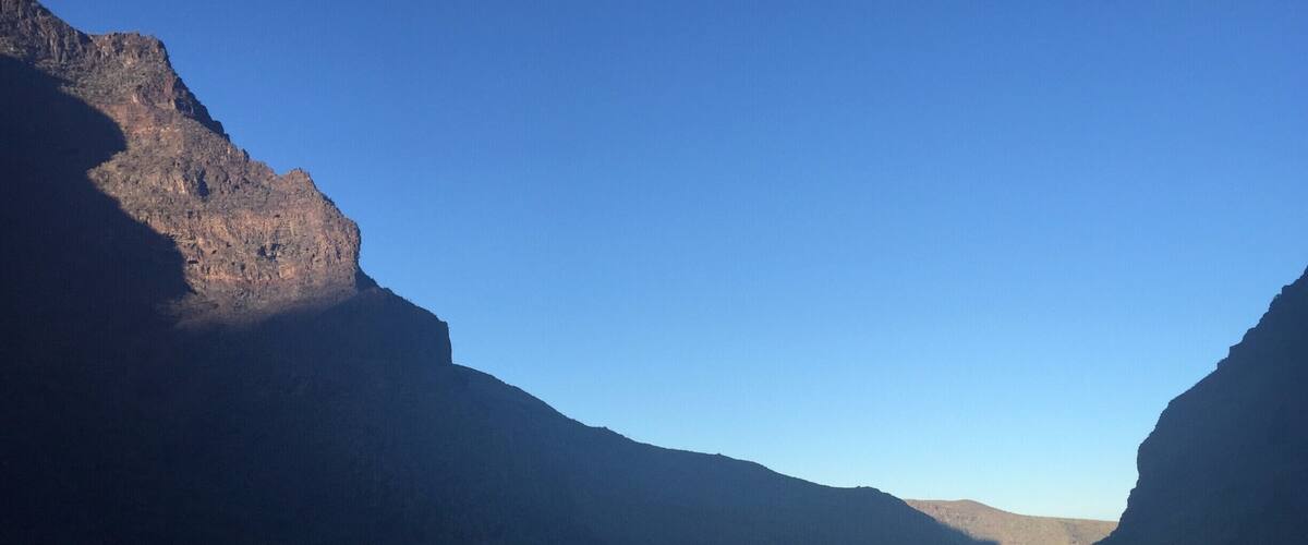 A canyon with steep cliffs and a clear blue sky.