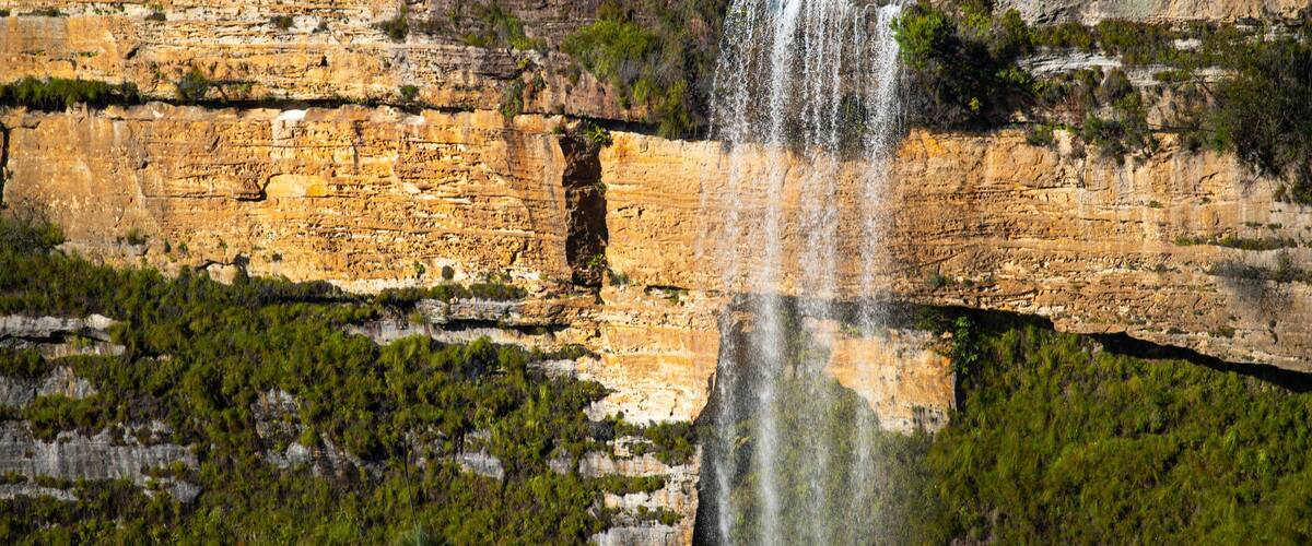 A waterfall cascading down a rocky cliff surrounded by greenery.