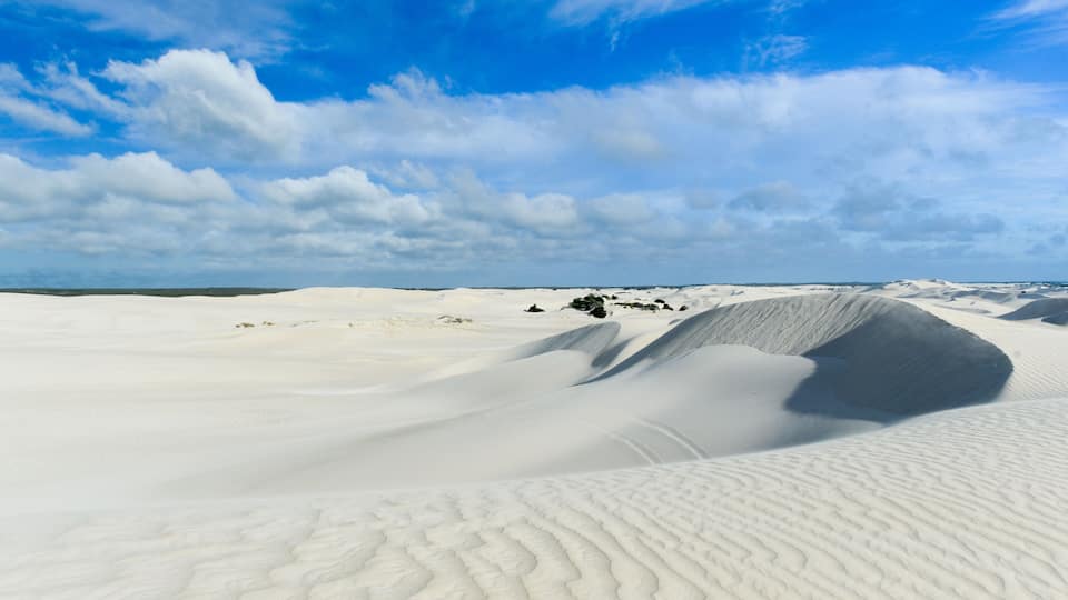 A vast white sand dune landscape under a clear blue sky.