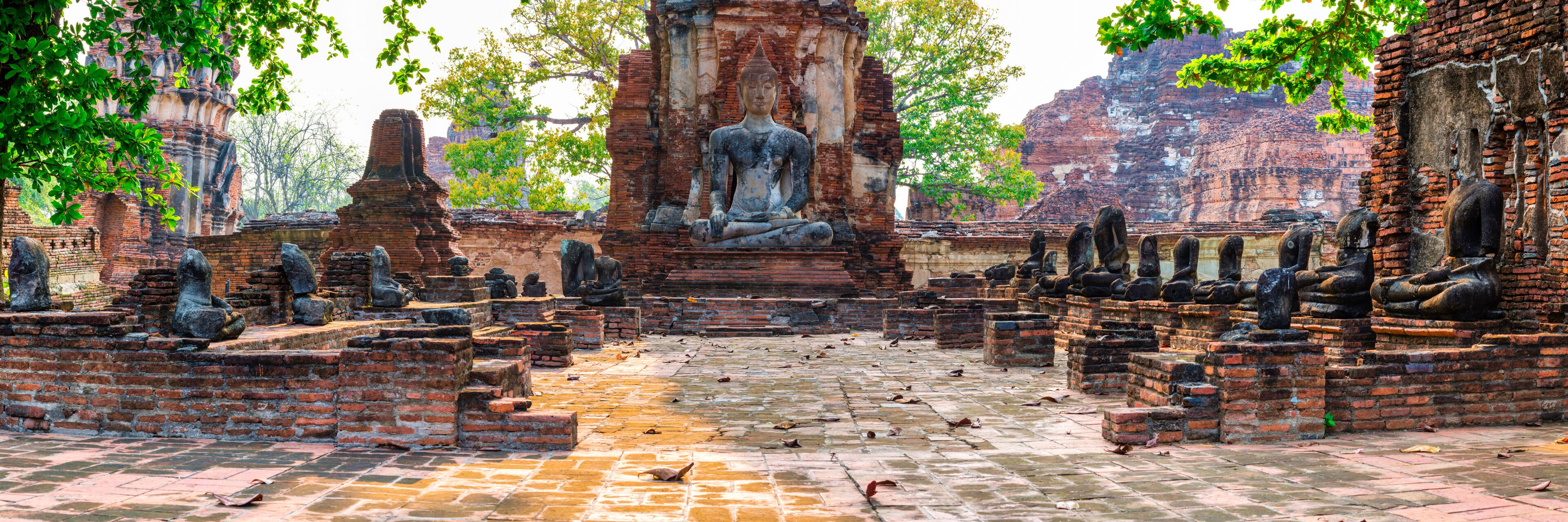 A temple complex with a central seated Buddha statue, surrounded by smaller statues and brick structures.
