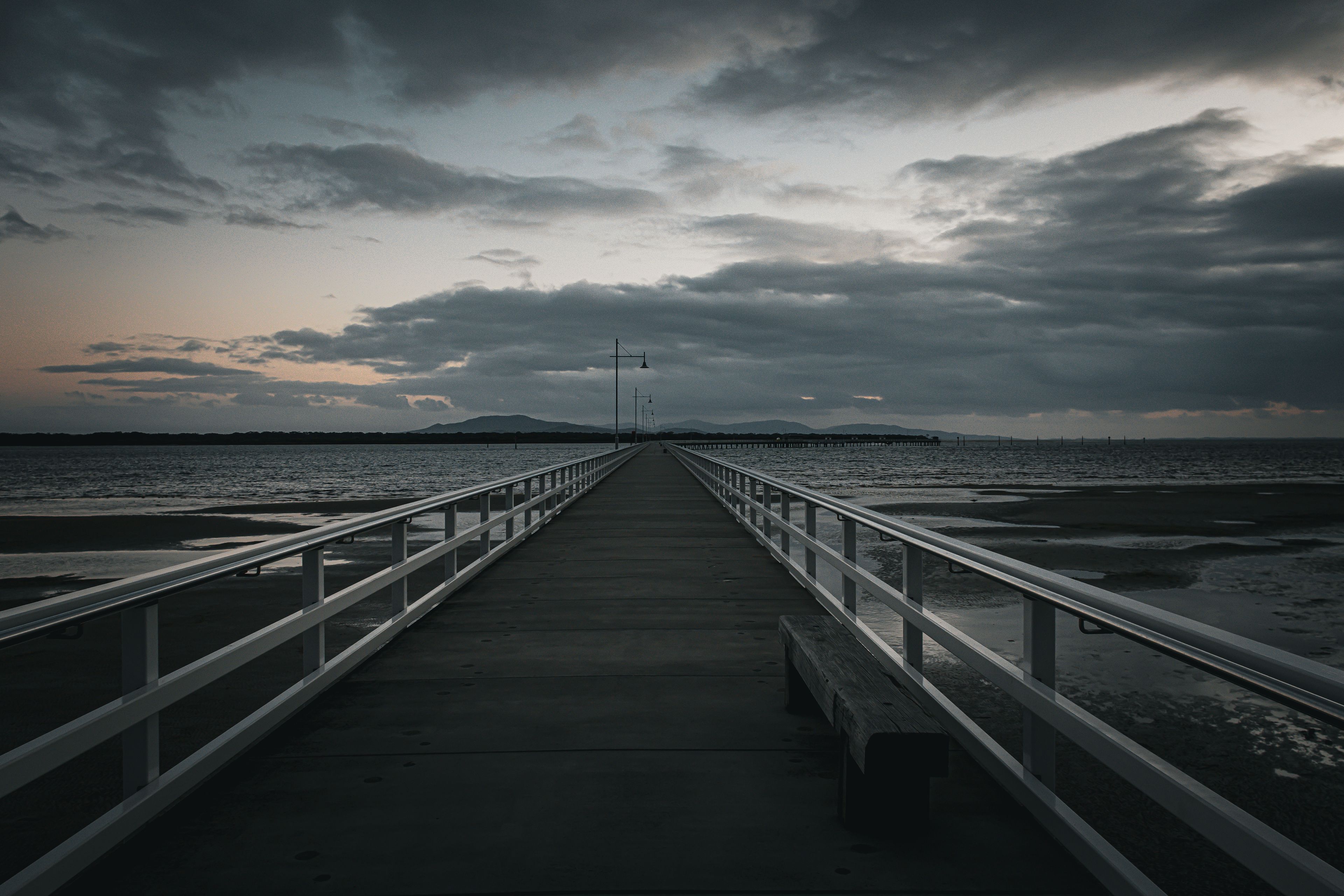The Port Welshpool Long Jetty in South Gippsland, Victoria, stretching into Corner Inlet under a dramatic, moody sky