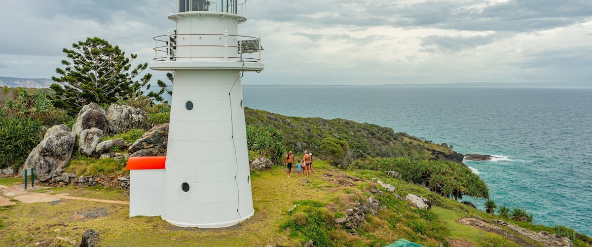Double Island Point Conservation Park featuring general coastal views and a lighthouse as well as a small group of people