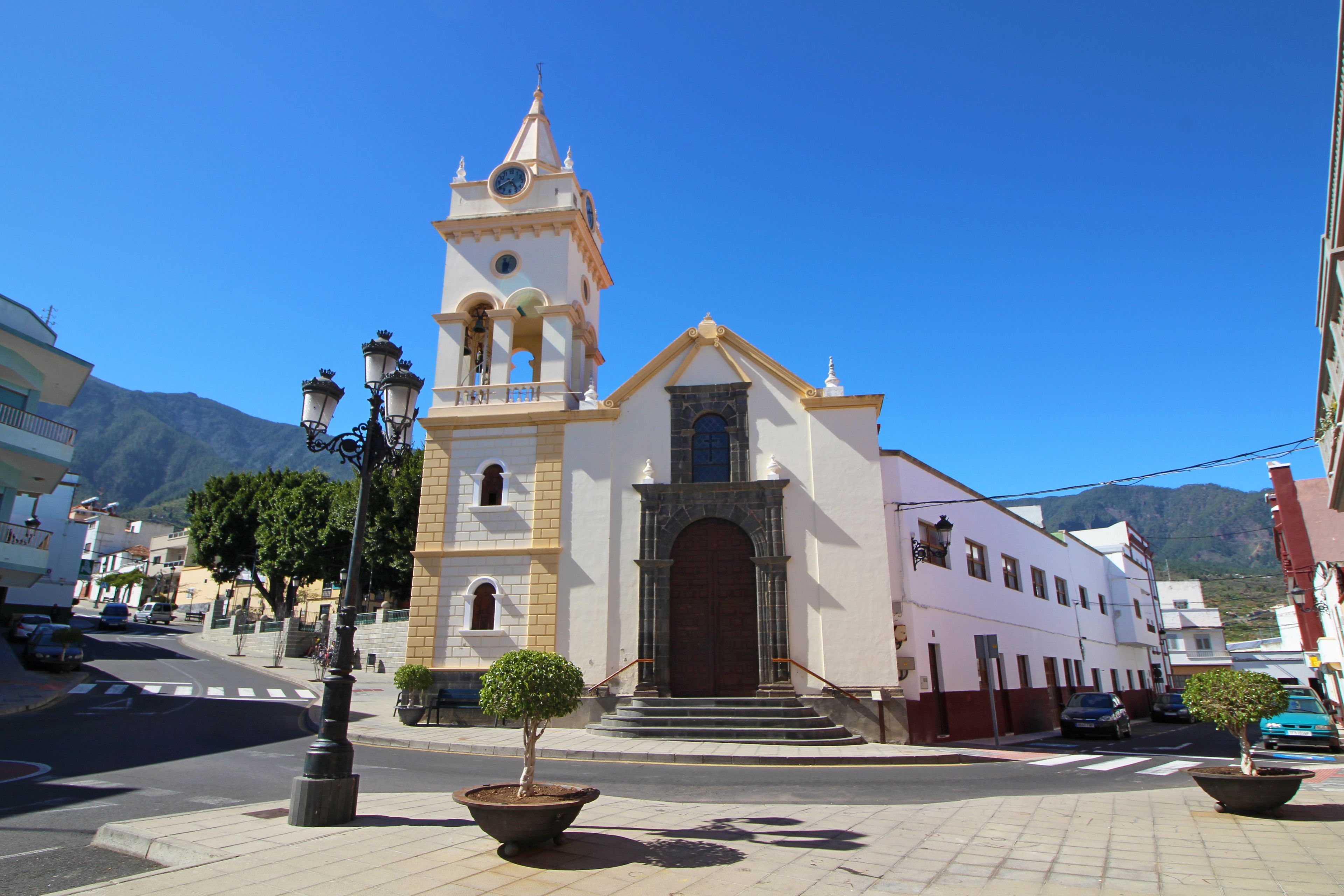 A church with a bell tower, a clock, and a small tree in the foreground.
