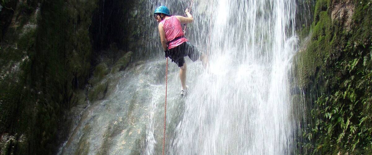A person rappelling down a waterfall.