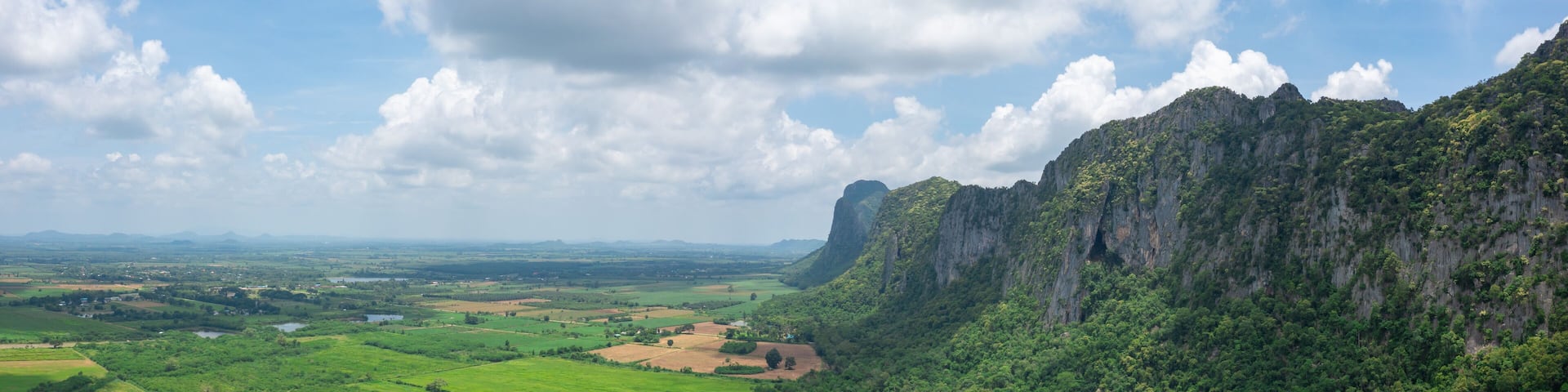 A lush green valley with a prominent limestone cliff and a small settlement.