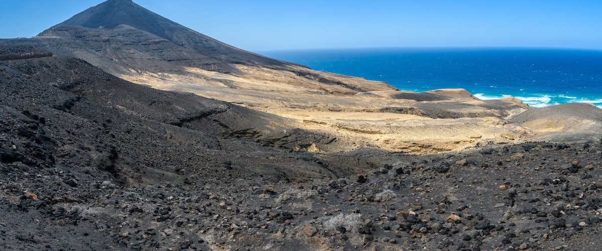 A volcanic landscape with a prominent mountain and a coastline.
