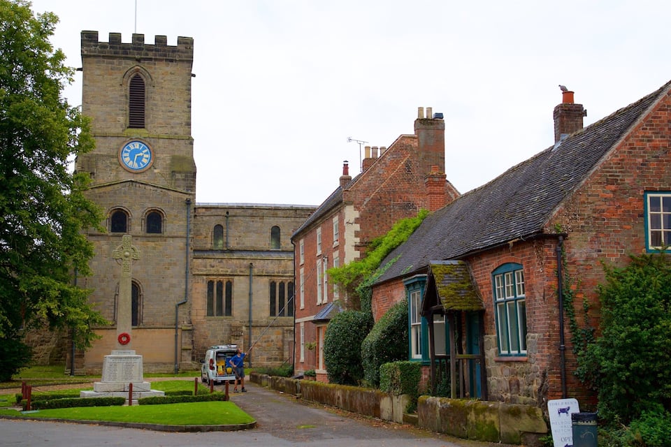 A historic church with a clock tower, a white van parked in front, and a sign for a butcher shop.