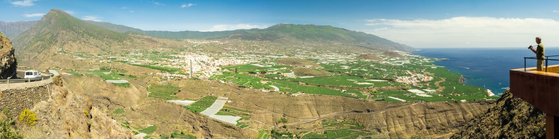 A mountainous landscape with terraced fields and a coastal view.