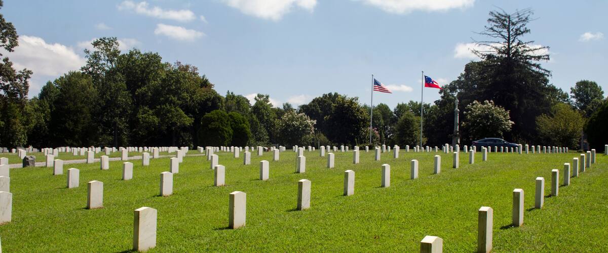 A cemetery with numerous headstones and two flags.