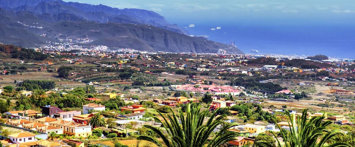 A coastal town with colorful houses, a mountain range, and the ocean.