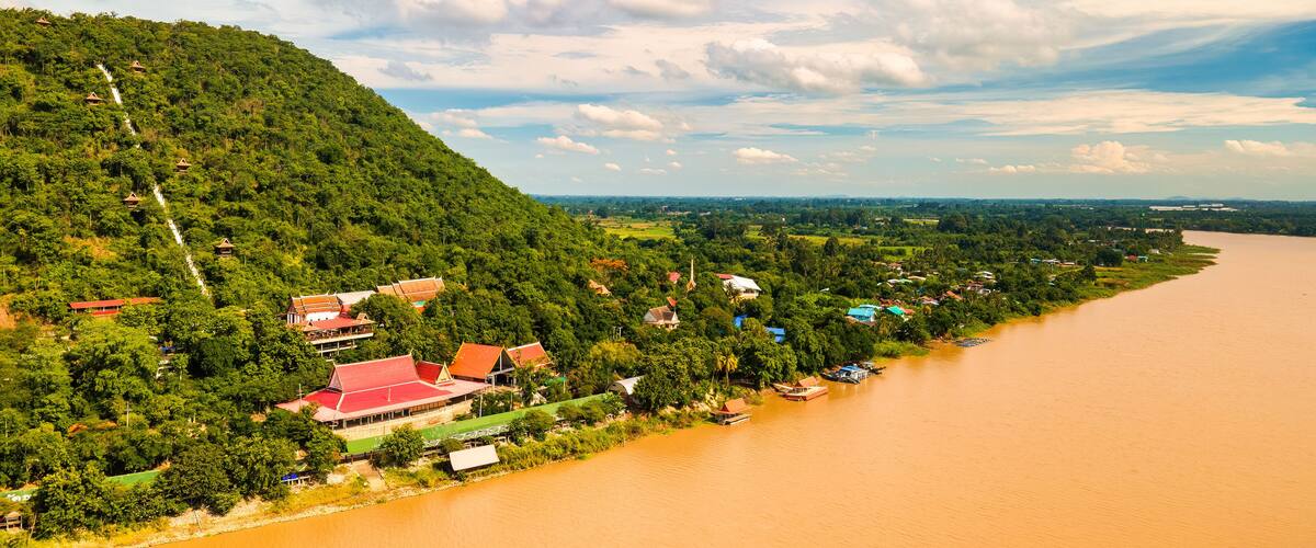 A river with houses and a hill with trees.
