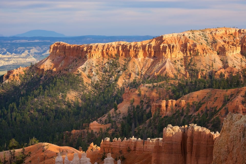 A rugged mountain landscape with prominent red rock formations and dense forests.