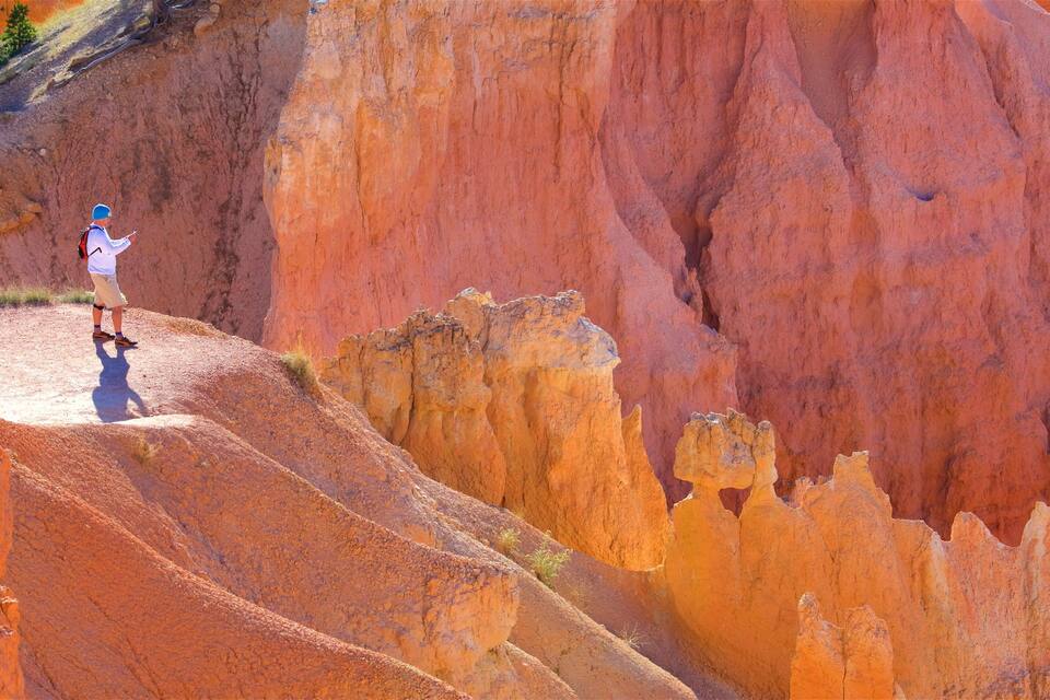 A rugged red rock landscape with hikers on a narrow ridge.